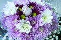 Purple and white posy bouquet of chrysanthemum flowers surrounding a single white rose