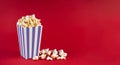 Purple white striped carton bucket with tasty cheese popcorn, isolated on red background