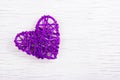 Purple wicker heart on a white wooden background. Eco Valentine. Heart of vines.