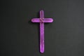 A purple wooden cross in black background. Christian faith, holy week or lent season celebration concept. Royalty Free Stock Photo