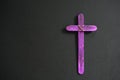 A purple wooden cross in black background. Christian faith, holy week or lent season celebration concept. Royalty Free Stock Photo