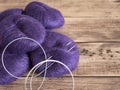 Purple yarn and needles for knitting. Balls of thread and fixed circular knitting needles on rustic wooden background