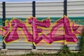 Purple,yellow and pink graffiti on a noise barrier wall