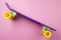 Purple youth skateboard on pink background. children`s plastic mini cruiser board.