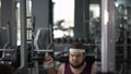 Purposeful chubby man doing sit-ups with barbell looking at his reflection