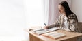 Purposeful female student studying with writing reference book, doing homework, concentrated teenage girl making notes Royalty Free Stock Photo