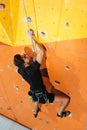 Purposeful man climbing up the wall in gym
