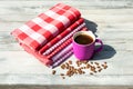 Purpure cup of hot black coffee with roasted coffee beans together with a Stack of red white checkered and striped linen Royalty Free Stock Photo