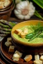 Purred creamy asparagus soup in glass bowl on black plate against raw fresh asparagus and greenery Royalty Free Stock Photo