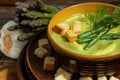 Purred creamy asparagus soup in glass bowl on black plate against raw fresh asparagus and greenery Royalty Free Stock Photo