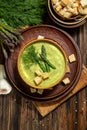 Purred creamy asparagus soup in glass bowl on black plate against raw fresh asparagus and greenery Royalty Free Stock Photo