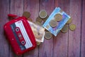 A purse with cassette shape and money on wooden table Royalty Free Stock Photo