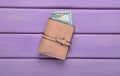 A purse with dollar bills on a pink wooden table. Top view Royalty Free Stock Photo