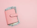 Purse with one hundred dollars banknotes on pink background. Flat lay, top view, copy space Royalty Free Stock Photo