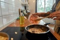 Pursue the flavor. Close up of man adding shrimp to sauteed garlic and onion in the frying pan. Cook preparing dish with