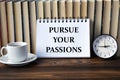 PURSUE YOUR PASSIONS - words on white notebook on background of books, clock and cup of coffee Royalty Free Stock Photo