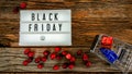 Push cart with  gifts and light box with black Friday text on rustic table Royalty Free Stock Photo