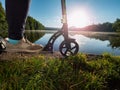 Push scooter on the lawn at park lake against sun Royalty Free Stock Photo