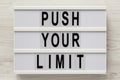 `Push your limit` words on a lightbox on a white wooden background, top view. Overhead, from above, flat lay. Close-up