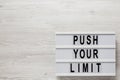 `Push your limit` words on a lightbox on a white wooden background, top view. Overhead, from above, flat lay. Copy space