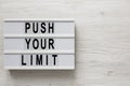 `Push your limit` words on a lightbox on a white wooden surface, top view. Overhead, from above, flat lay. Space for text