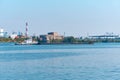 Towboat pushes dry bulk cargo barge on the river against the backdrop of an industrial landscape on the shore Royalty Free Stock Photo