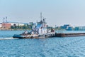 Towboat pushes dry bulk cargo barge on the river in an industrial landscape Royalty Free Stock Photo