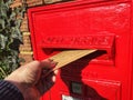 A hand posting a letter in a mail box