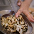 Pushing slices of brown button mushroom on metal plate.