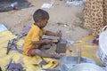 A little Indian boy uses tools instead of toys next to a hut in the holy city Pushkar, Rajasthan, India, close up portrait