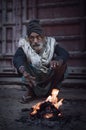 A homeless Indian elder keeping warm by the fire