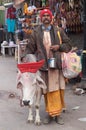 Sadhu with cow seeking alms on the street in Pushkar, India Royalty Free Stock Photo