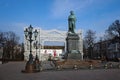 Pushkin monument by Opekushin in Pushkinskaya square with view of decorative arch in front of Rossiya cinema.