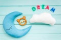 Put baby into bed with moon pillow, clouds, toy and dream copy on mint green wooden background top view