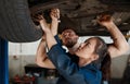 They put the care in autocare. two mechanics working together under a lifted car. Royalty Free Stock Photo