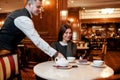 Put customers first. Confident waiter serving desserts and coffee to costumers. Couple having breakfast in hotel