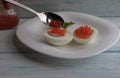 Put a spoonful of red caviar on boiled eggs, on a plate. Royalty Free Stock Photo