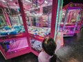 Putrajaya, Malaysia - January 16, 2023 Happy little girl Playing the claw machine at the garme arcade. Viewed from behind