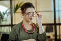 Young prosperous businesswoman putting her glasses on