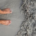 Putting man feet inside the water wave on a sandy beach Royalty Free Stock Photo