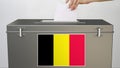 Putting paper ballot into ballot box with flag of Belgium. Voting related 3d rendering