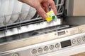 Putting tab into full dishwasher close up. integrated dishwasher machine full loaded. woman hand holding dishwasher Royalty Free Stock Photo