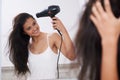 Putting together her hairstyle. A young woman blowdrying her hair.