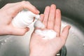 Putting whip foam soap bottle with foam on female hand. Lady using alcohol gel as hand sanitizer