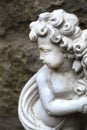 Putto or angel figurine in front of an old stone wall