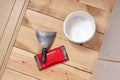 A putty bucket, trowel and emery grater are on the floor. Nearby is a wall of plasterboard and sheets of fibreboard. The floor of