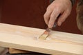 Putty knife in old man`s hand. Removing paint from a wood surface. Preparation of boards before impregnation with