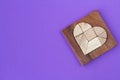 Puzzle details in wooden heart-shaped box on purple background Royalty Free Stock Photo