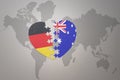 Puzzle heart with the national flag of australia and germany on a world map background. Concept Royalty Free Stock Photo