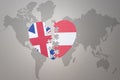 Puzzle heart with the national flag of austria and great britain on a world map background. Concept Royalty Free Stock Photo